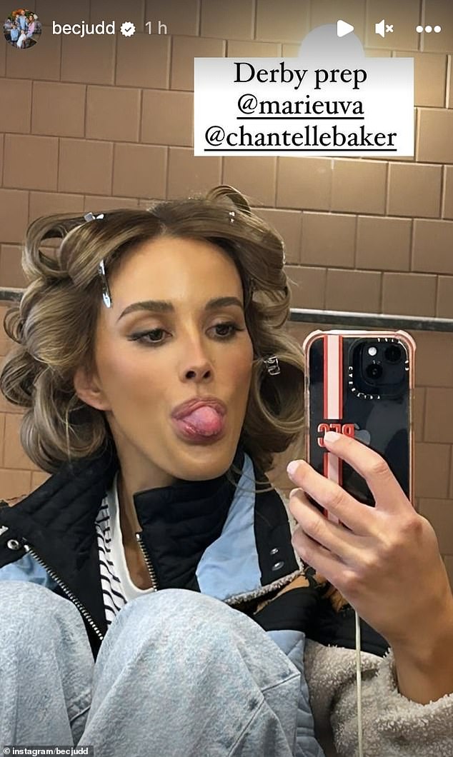 Ребекка Джадд опубликовала фотографию, на которой она сидит в кресле с большими бигуди в волосах после завершения макияжа.