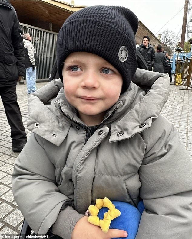 Бо, единственный ребенок Хлои, родившийся в 2019 году, согревался в черной шляпе и крепко держался за сине-желтую мягкую игрушку.
