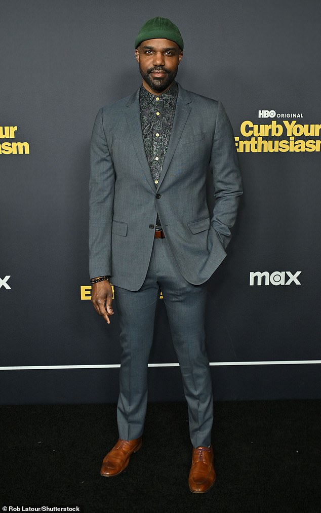 Карл Клемонс-Хопкинс был красив в сером костюме и зеленой шапке.