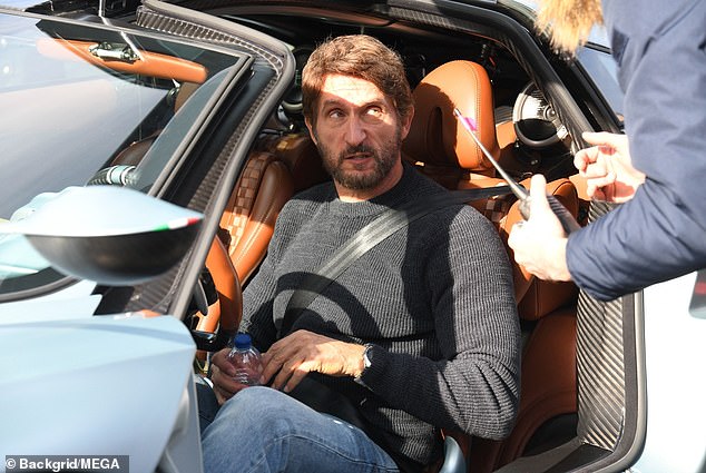 На снимке Джонатан получает указания, сидя в синем Pagani.