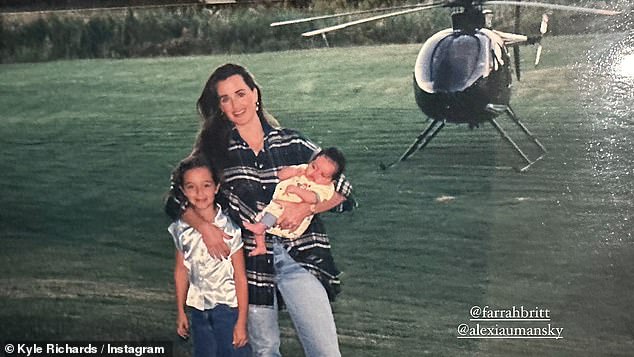 На другой фотографии звезда реалити-шоу была одета в большую синюю клетчатую рубашку и джинсы, держа на руках малышку Алексис.  Она обнимает свою дочь Фарру, стоящую на берегу озера, на заднем плане парит вертолет.